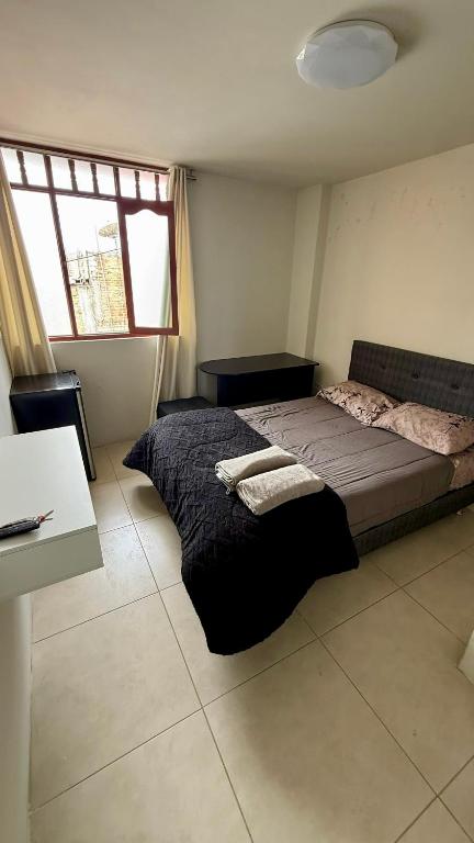 a bedroom with a bed and a desk and a window at Habitación Matrimonial en el centro de la ciudad in Ayacucho