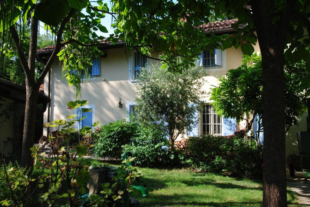 uma casa branca com janelas azuis e um quintal em Alle Rive Bed'n'Books Apt em Calamandrana