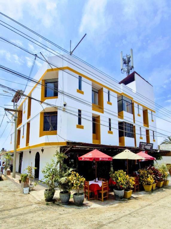 a yellow and white building with tables and umbrellas at Hostal los pulpos in Bombiso