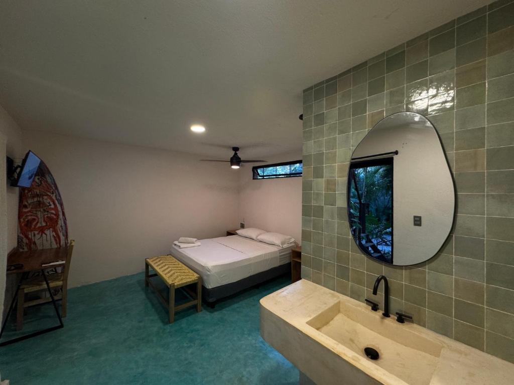 a bathroom with a bed and a sink and a mirror at La punta surfhouse 2 in Puerto Escondido