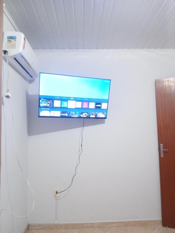 a flat screen tv hanging on a wall at Quarto com ar condicionado tv para uma pessoa in Passo Fundo