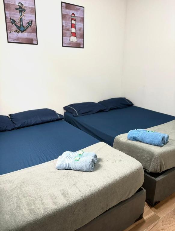 a room with two beds and two ottomans at Pousada Lemon Quartos Casal e Família - Ar condicionado e Frigobar - Sesc Bertioga in Bertioga