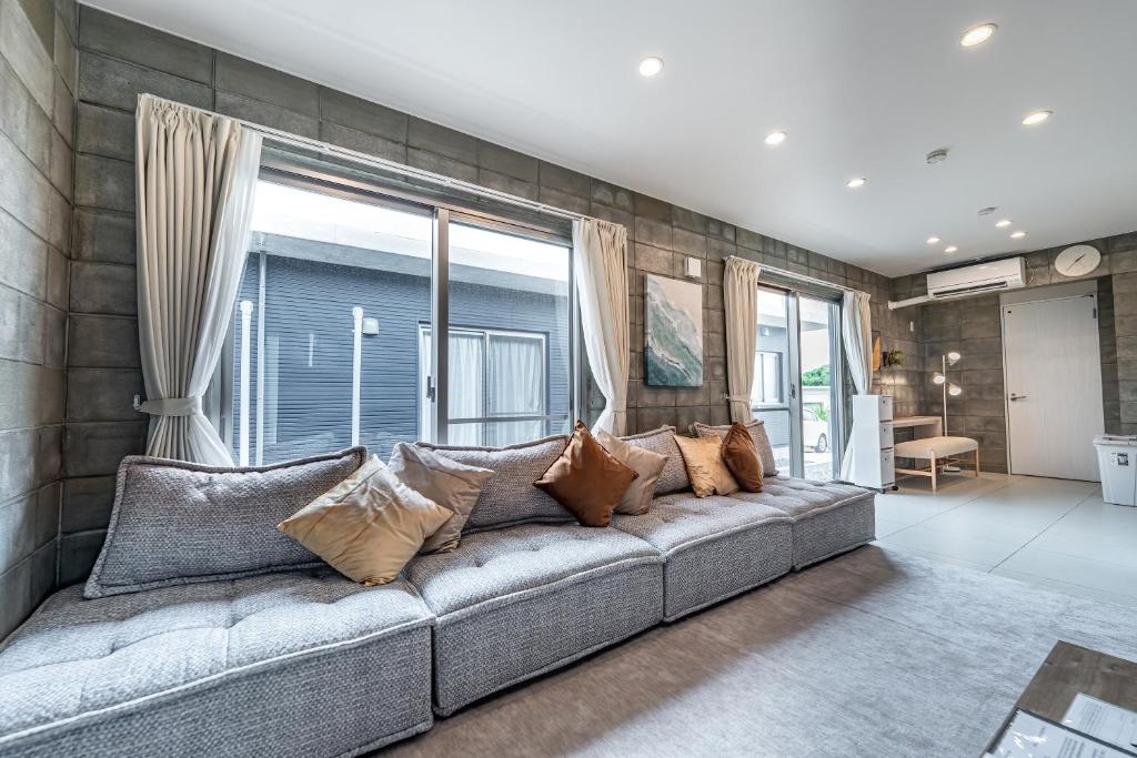 a living room with a gray couch with pillows at Hale Twelve AB in Miyako-jima