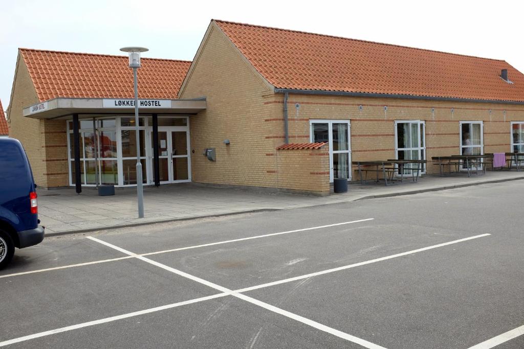 a building with a parking lot in front of it at Løkken Hostel in Løkken