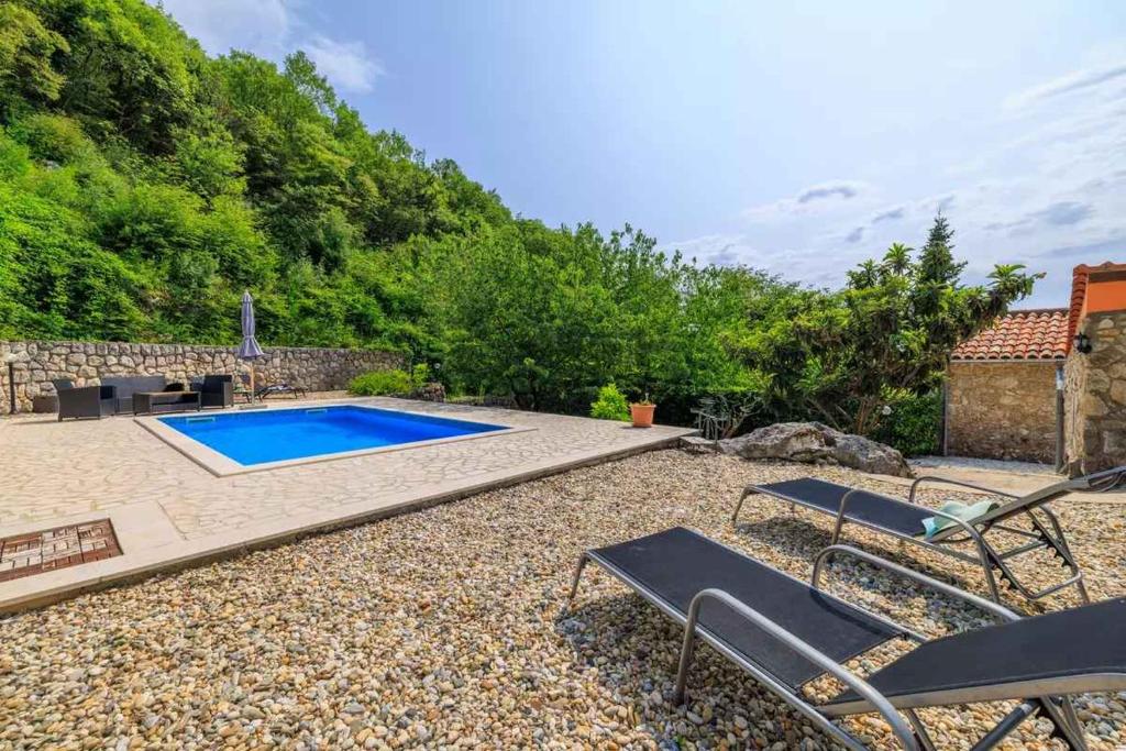 a backyard with a swimming pool and two chairs at Holiday home in Marusici - Istrien 39238 in Grižane