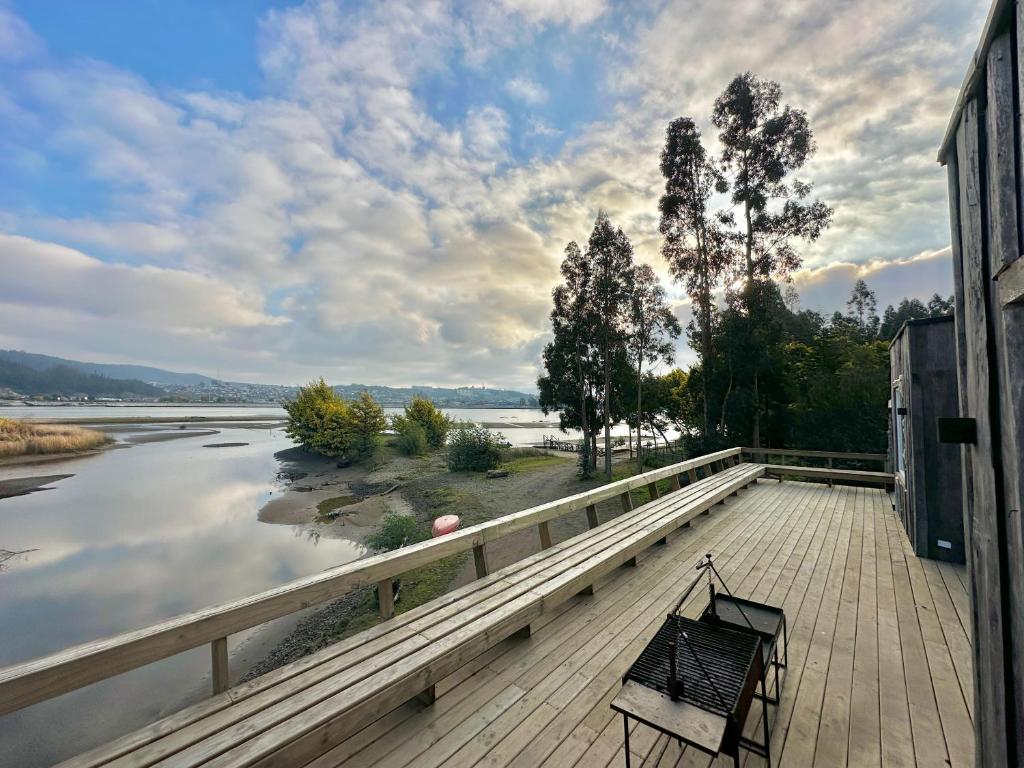 Un banco sentado en una terraza junto a un río. en House in the Maule River Bay, en Constitución