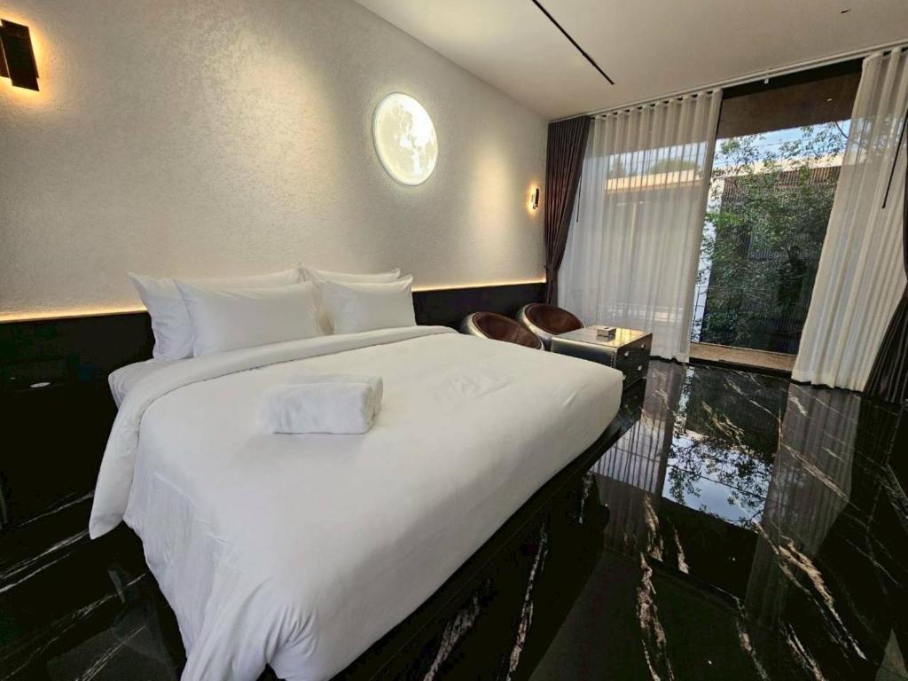 Un dormitorio con una cama blanca grande y una ventana en Khanom Station 549, en Ban Na Dan