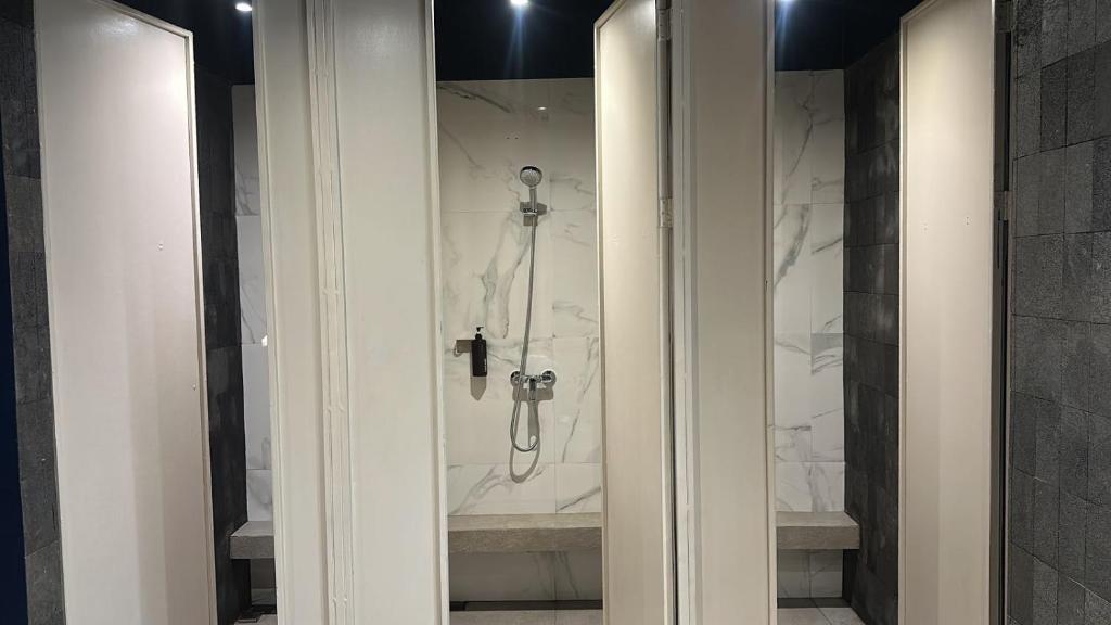 a shower in a bathroom with white marble walls at Althia Capsule Quarters in Badung