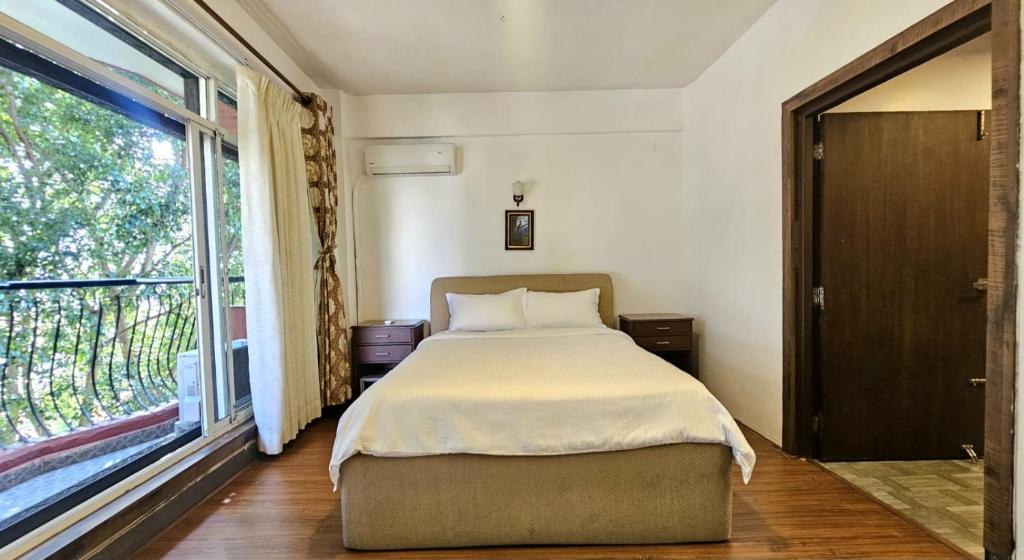 a bedroom with a bed and a large window at Sagarmatha Apartment Hotel in Pātan
