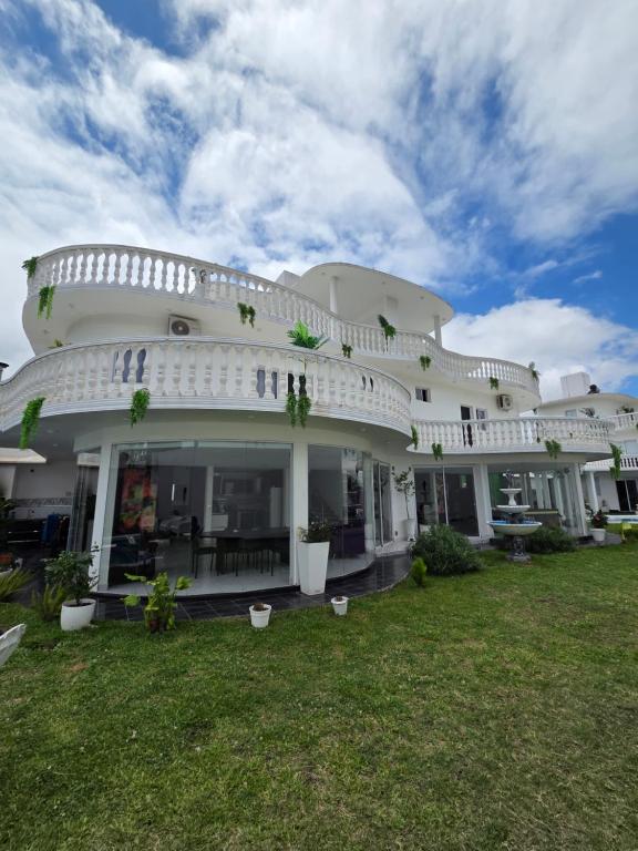 a large white building with a green yard at Alisos Suite FC Torre 2 in El Ceibal