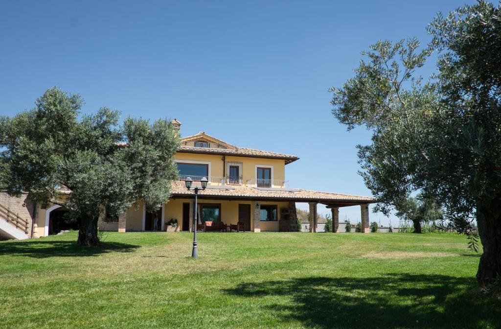 a house in a field with trees in the foreground at Villa Nadia, with an exclusive swimming pool in Monterosi