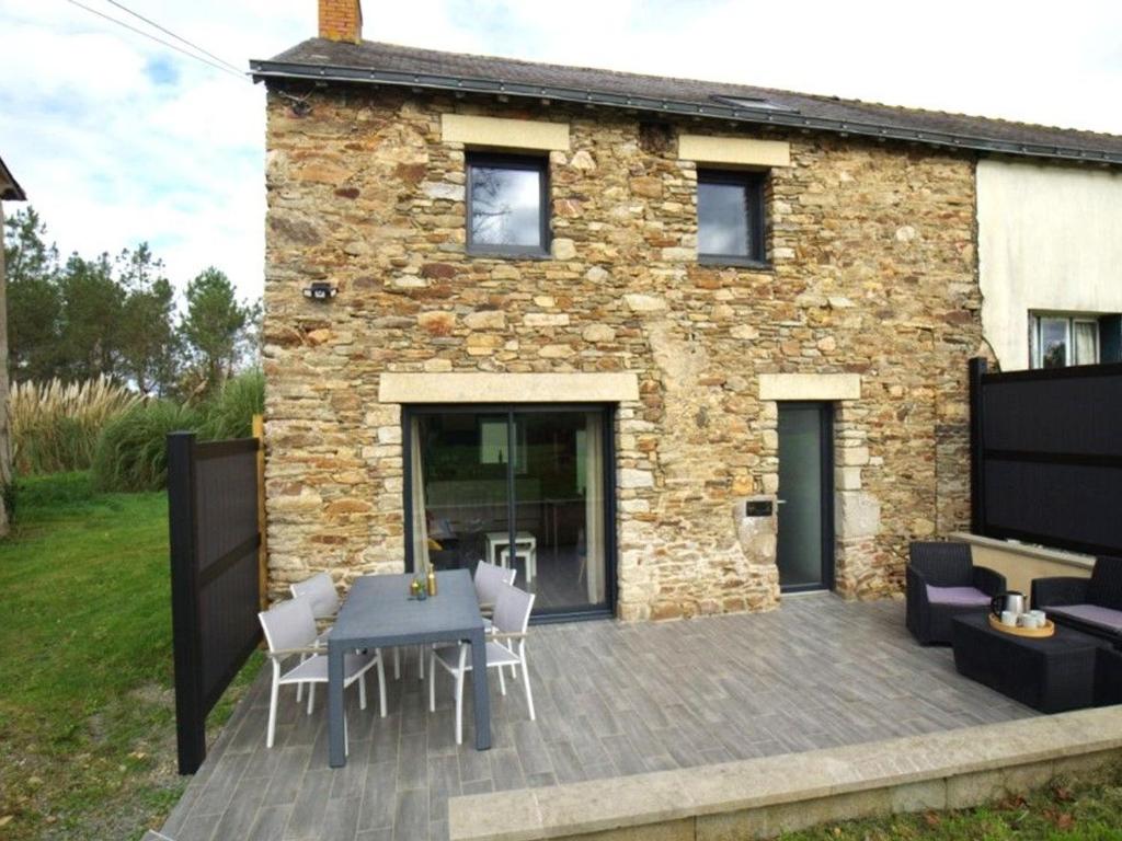 un patio avec une table et des chaises et un bâtiment dans l'établissement Charmante maison mitoyenne avec jardin et Wifi en campagne près de Nantes - FR-1-306-1320, à Bouvron
