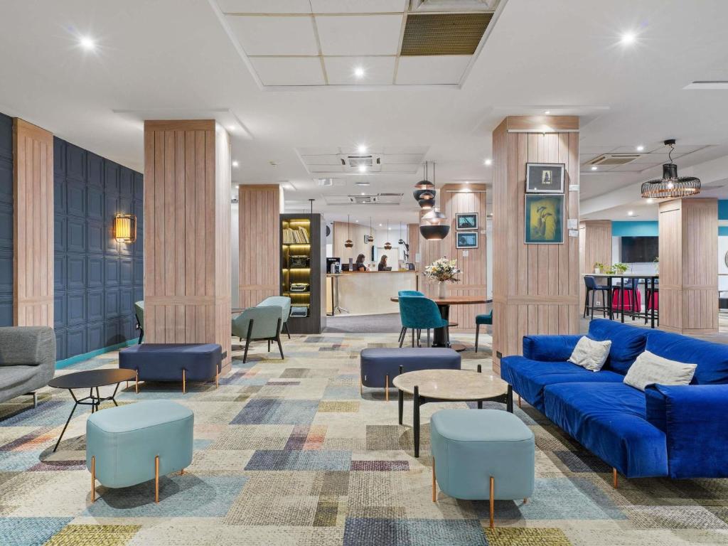- un hall avec un canapé bleu et des chaises dans l'établissement Mercure Paris Porte d'Orleans, à Montrouge