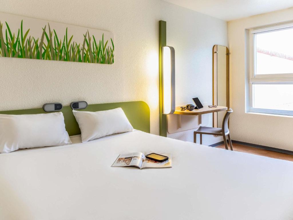 a bedroom with a white bed with a book on it at ibis budget Compiègne Centre-Ville in Compiègne