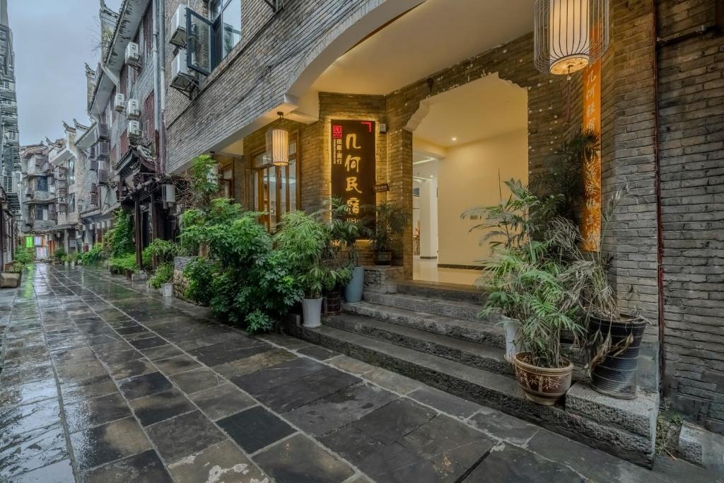 een straat met potplanten voor een gebouw bij Phoenix Geometry Light Accommodation in Fenghuang