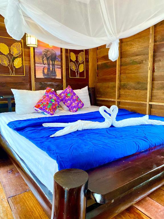 two swans laying on a bed with blue sheets at Lucky Resort in Ko Phayam