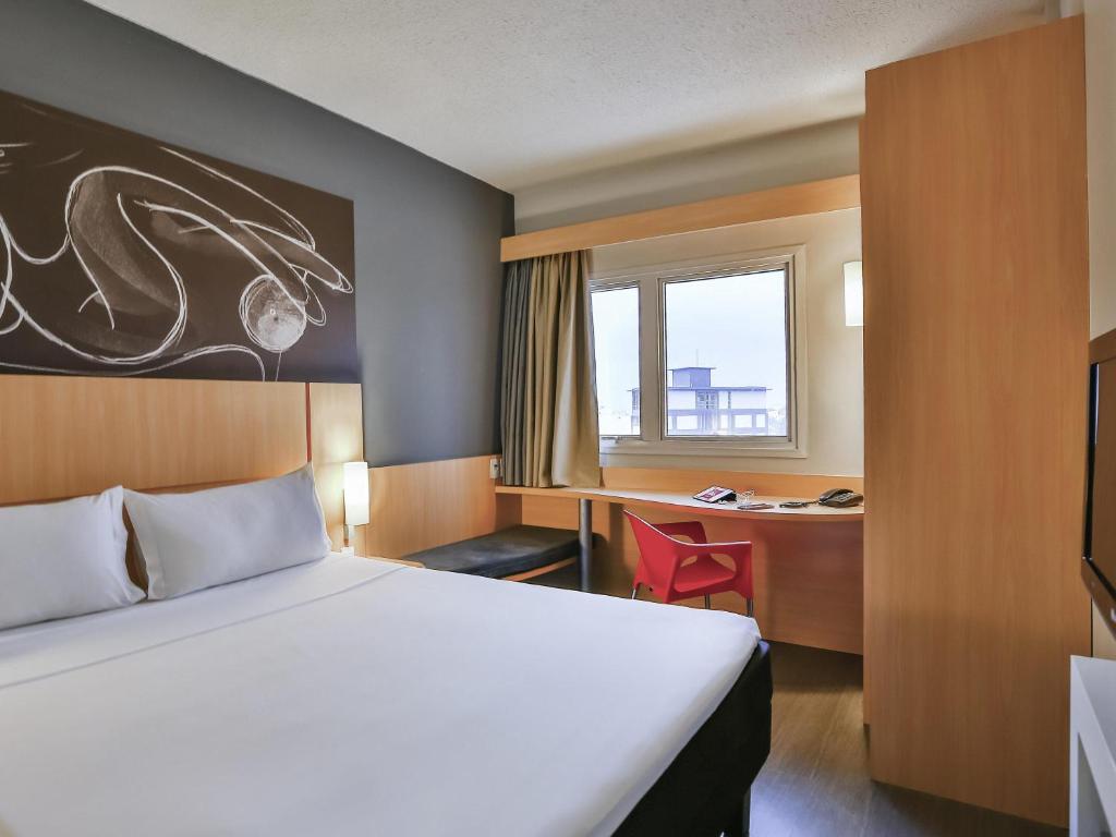 a hotel room with a bed and a desk at ibis Goiânia in Goiânia