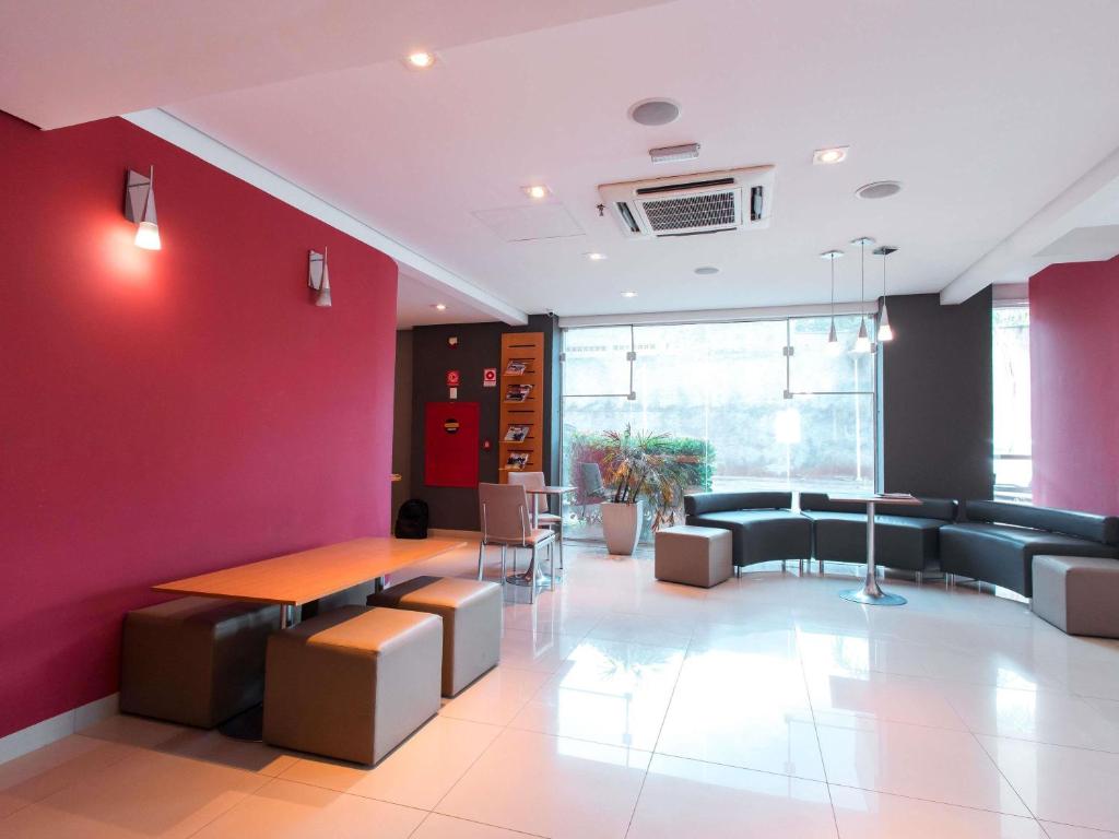 um quarto com uma parede vermelha e uma mesa e cadeiras em ibis Presidente Prudente Manoel Goulart em Presidente Prudente
