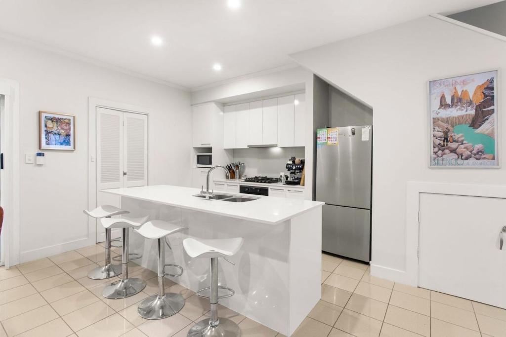 eine weiße Küche mit einer Theke und einem Kühlschrank in der Unterkunft Executive Townhouse Near Heart of Adelaide City in Rose Park