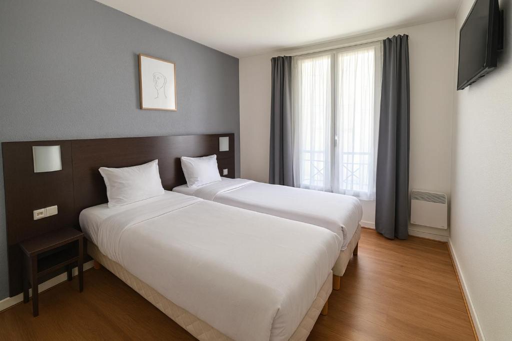 a hotel room with a large bed and a window at Hotel Arc Paris Porte d'Orléans in Montrouge