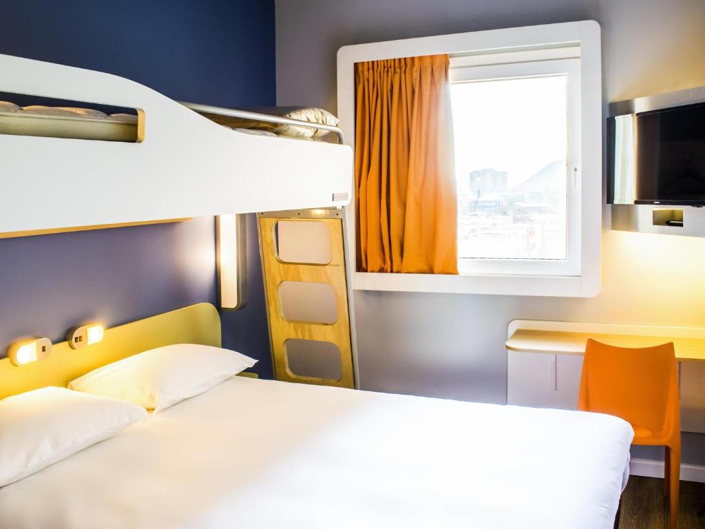 a bedroom with a bed and a desk and a window at ibis budget Copiapo in Copiapó