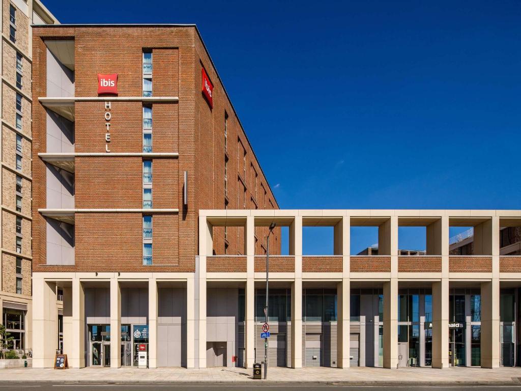 a large brick building with a red sign on it at ibis London Canning Town in London