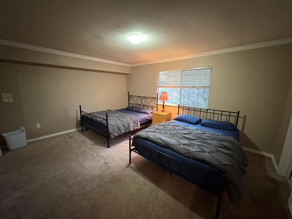 Un dormitorio con dos camas y una ventana. en North Delta Guest House Near Scott Rd, Transit, Airport 20 Min, Free Parking, en Delta