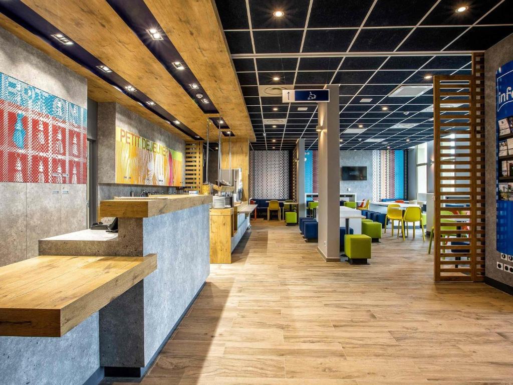 an office lobby with a bar and tables and chairs at ibis budget Paris Gennevilliers in Gennevilliers