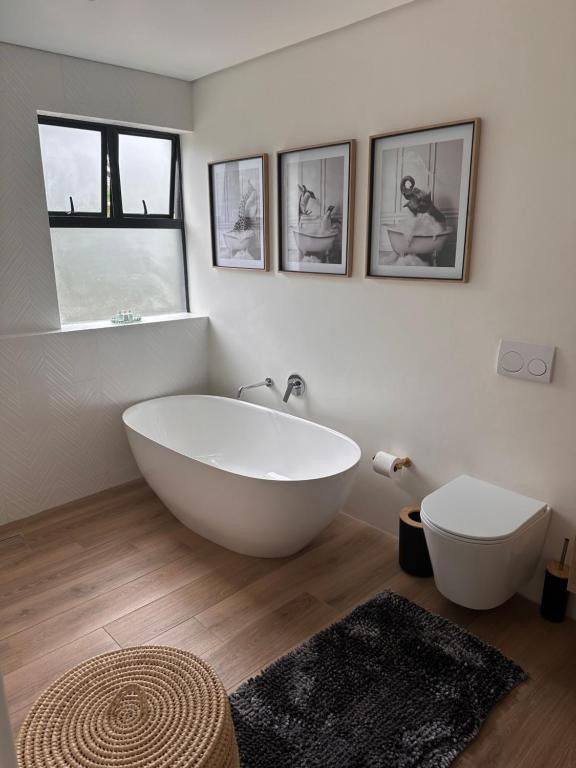 a bathroom with a large white tub and two windows at Two Tides in Ballito