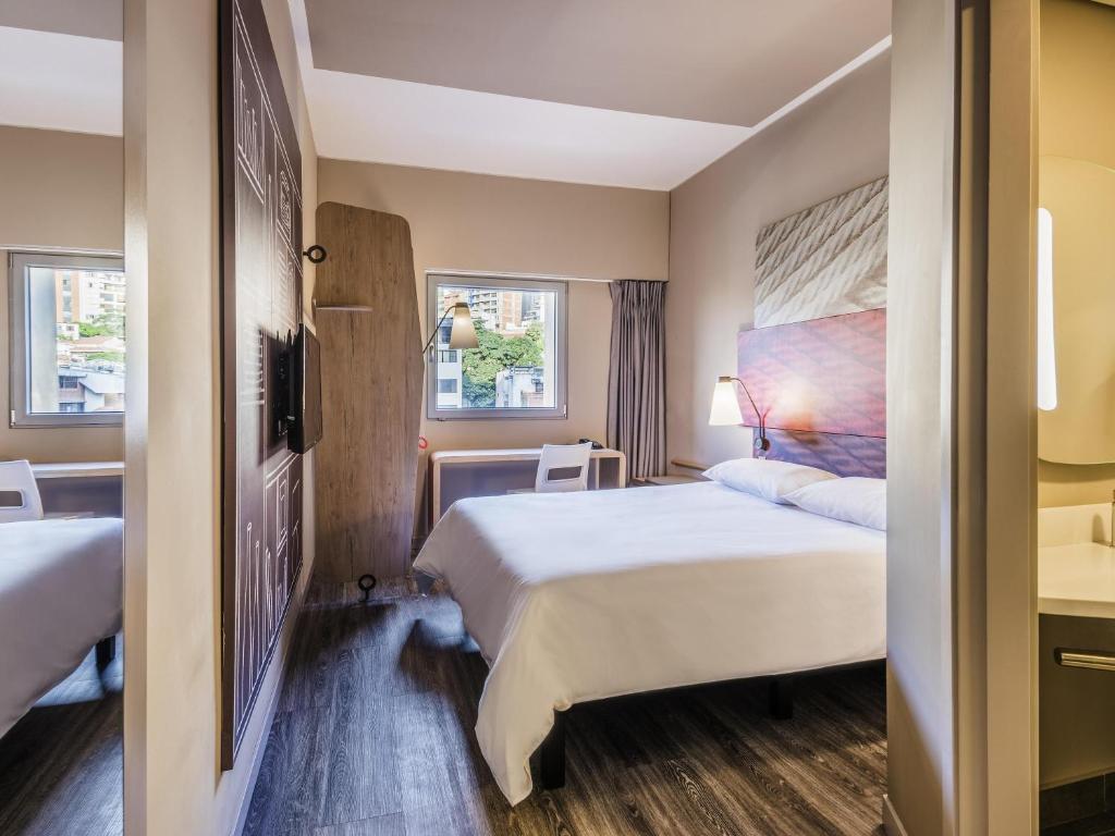 a hotel room with two beds and two windows at Hotel Ibis Cali Granada in Cali