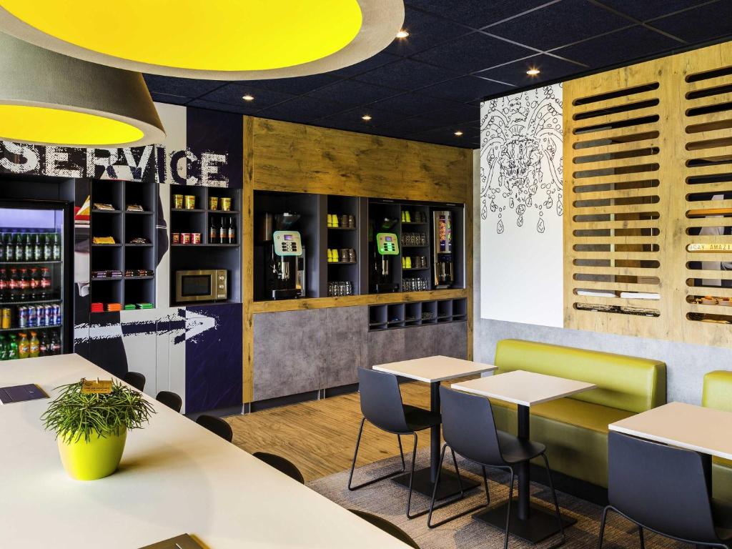 a restaurant with tables and chairs and wine bottles at ibis budget Stein Maastricht in Stein