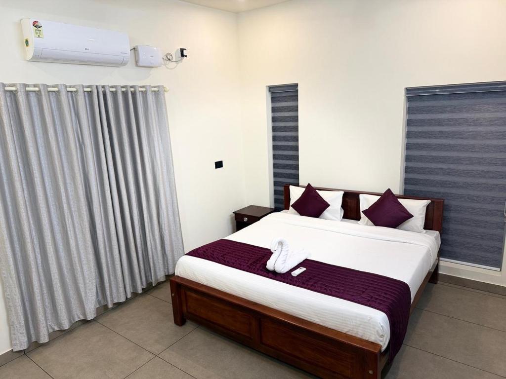 - une chambre avec un grand lit et des oreillers violets dans l'établissement Casa Linda Residency, à Varkala
