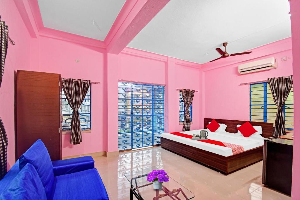 a bedroom with pink walls and a bed and a couch at Hotel O New Orchid Inn in Kolkata