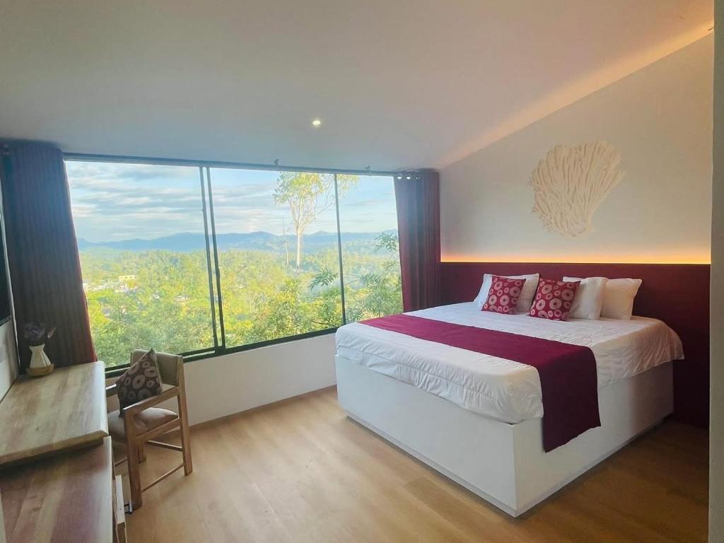a bedroom with a bed and a large window at 1818 UVA in Bandarawela