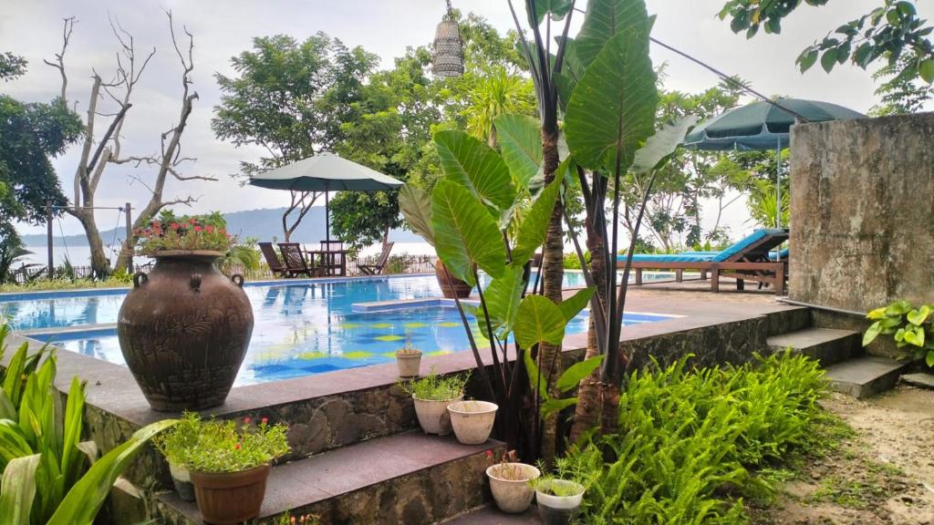 Una piscina de resort con un gran jarrón y plantas. en Rumah Arunika 27, 