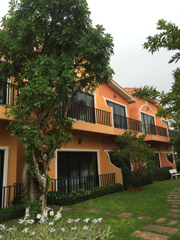 an orange building with a tree in front of it at Sata House Boutique Resort in Nakhon Ratchasima