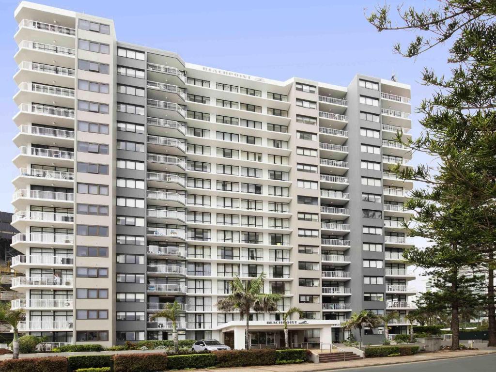 un grand immeuble d'appartements blanc avec des arbres devant lui dans l'établissement BreakFree Beachpoint, à Gold Coast