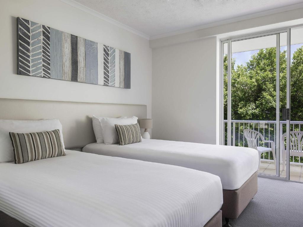 two beds in a hotel room with a balcony at BreakFree Diamond Beach in Gold Coast