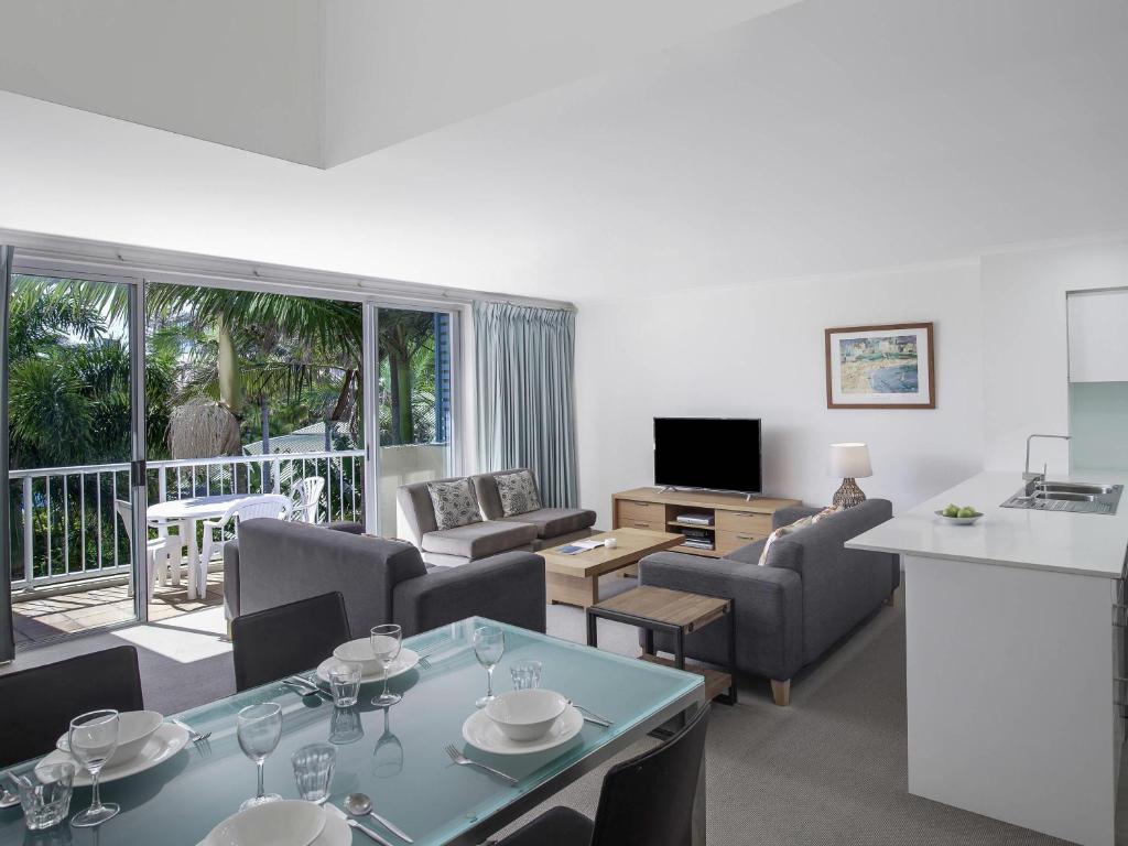 a living room with a table and chairs and a kitchen at BreakFree Diamond Beach in Gold Coast