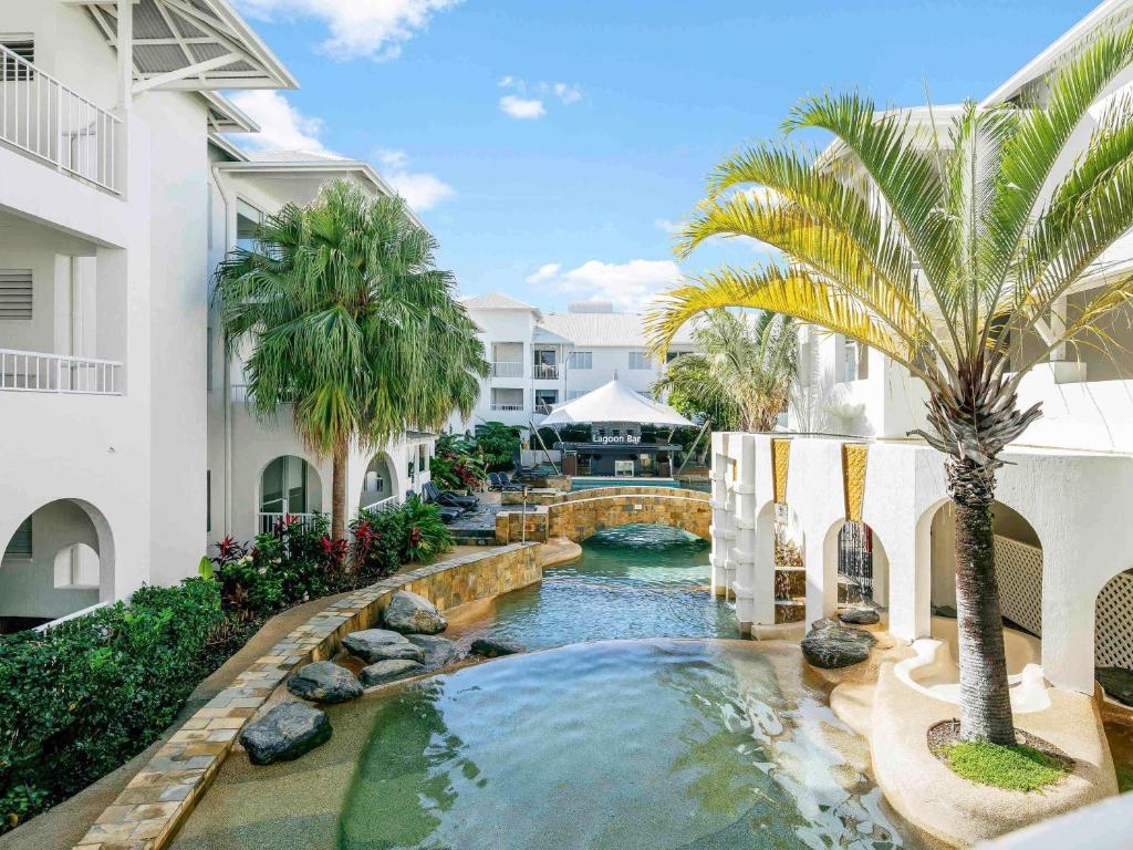 una piscina en el medio de un edificio con una palmera en Mantra PortSea, en Port Douglas