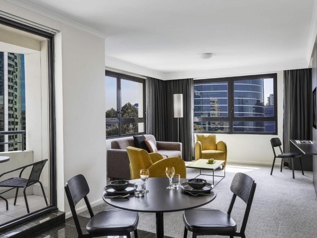 een woonkamer met een bank, een tafel en stoelen bij Mantra Parramatta in Sydney