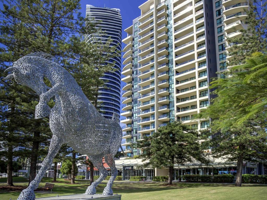 eine metallene Pferdestatue in einem Park mit hohen Gebäuden in der Unterkunft Mantra Broadbeach on the Park in Gold Coast
