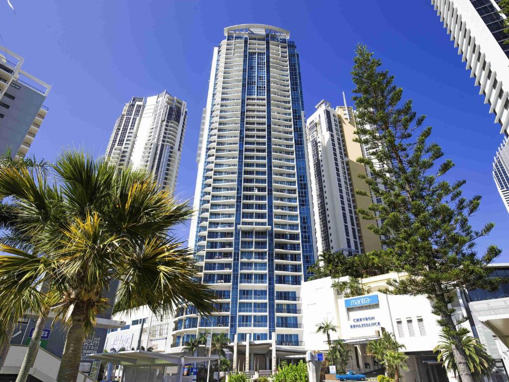 a tall building with palm trees in a city at Mantra Towers of Chevron in Gold Coast