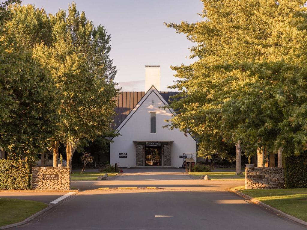 ein weißes Gebäude auf einer Straße mit Bäumen in der Unterkunft Peppers Clearwater Resort in Christchurch
