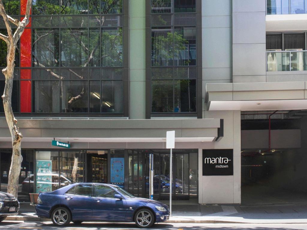 une voiture bleue garée devant un bâtiment dans l'établissement Mantra Midtown, à Brisbane