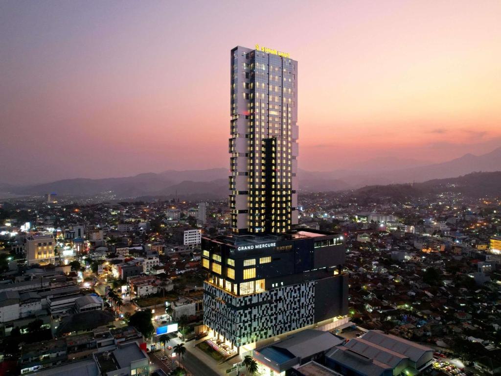 a tall skyscraper in a city at night at Grand Mercure Lampung in Bandar Lampung