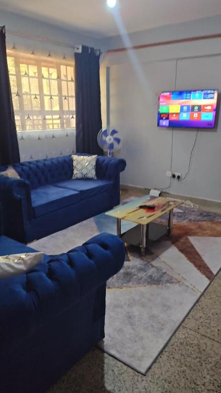 a living room with two blue couches and a table at MeHomes 1-Bedroom Apartment in Busia