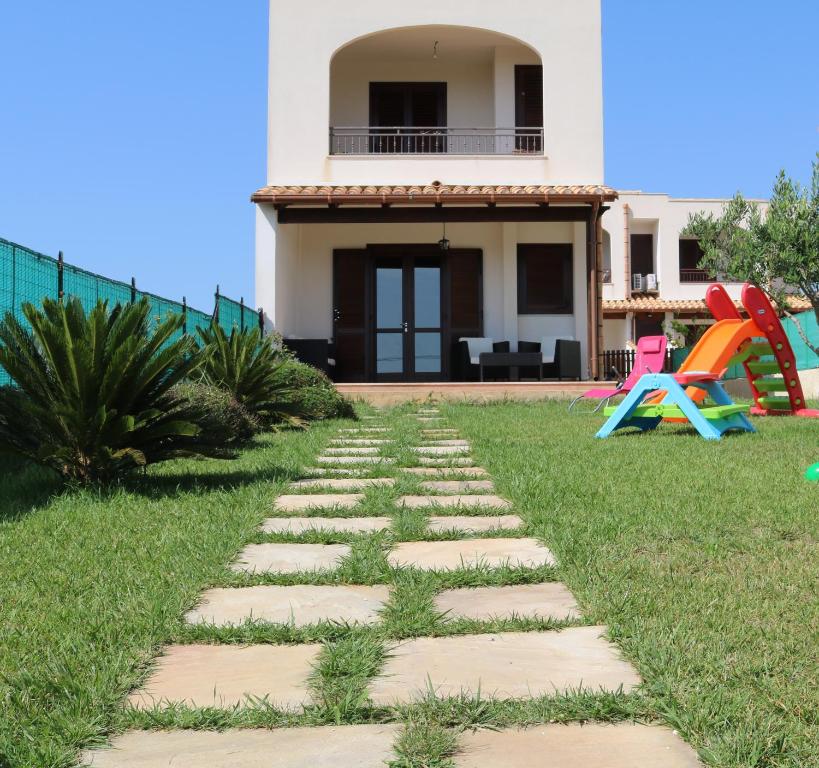 a walkway in front of a house with a playground at Villetta Airone in Birgi Vecchi