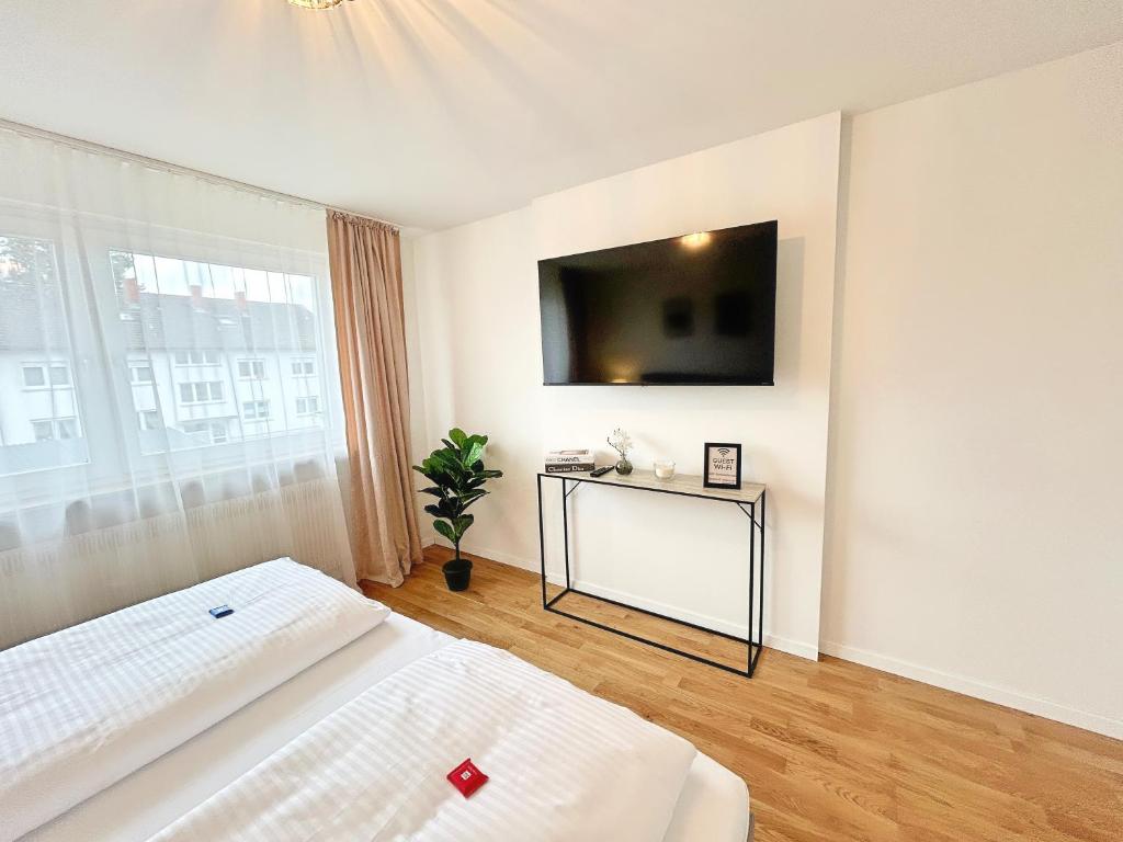 a bedroom with a bed and a tv on the wall at Basilisk Homes - in Grenzach-Wyhlen bei Basel - 4 x Moderne Fewos je 1bis2, 1bis4 oder 1bis6 Pers mit Küche und Balkon oder Terrasse - Parkplätze vorhanden in Grenzach-Wyhlen