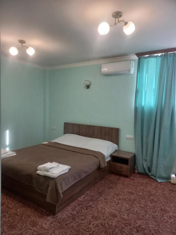 a bedroom with a bed and a blue curtain at Hotel International in Yerevan